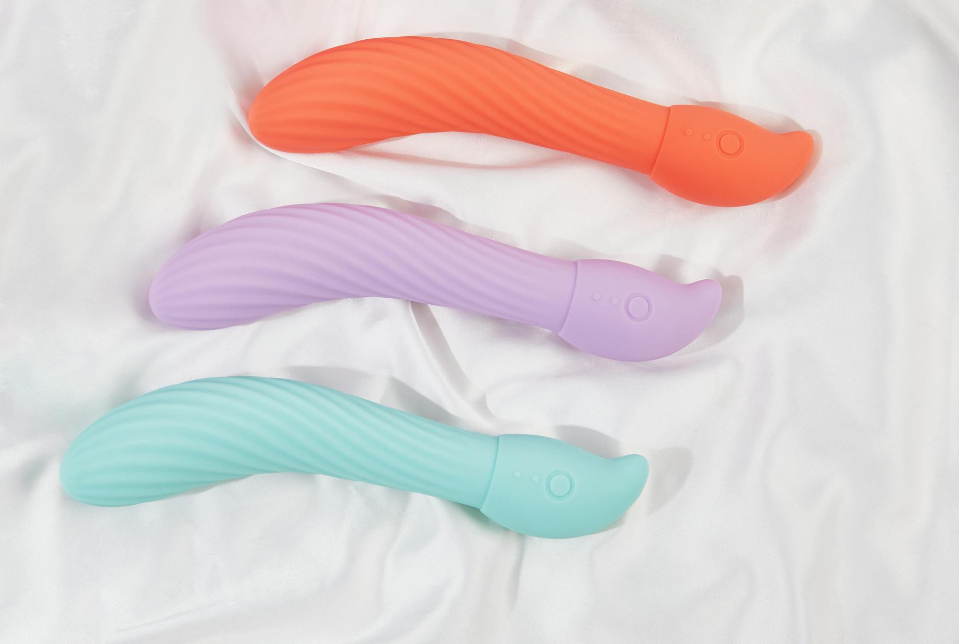 A teal lemon clitoral vibrator on smooth white silk fabric