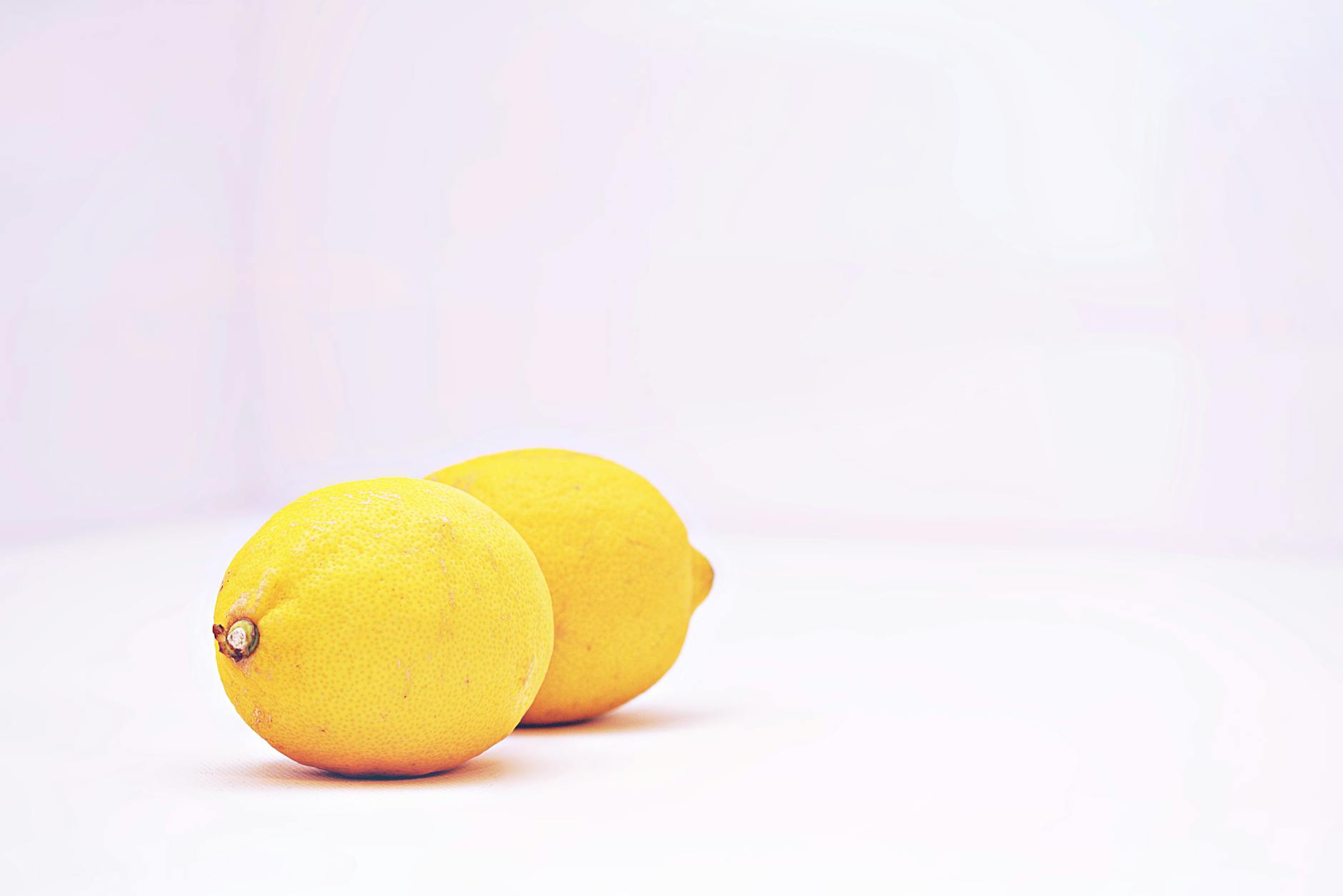 Two fresh lemons held in cupped hands on a brown surface, symbolizing fresh sensitivity awareness