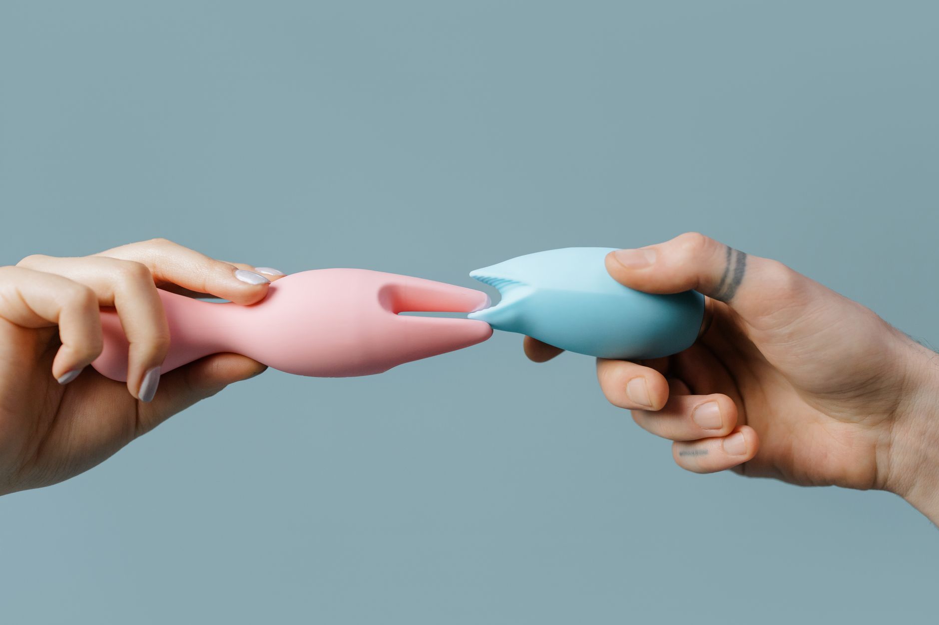 Hands holding a sleek blue vibrator against a purple background, symbolizing gentle sensation and reconnection.