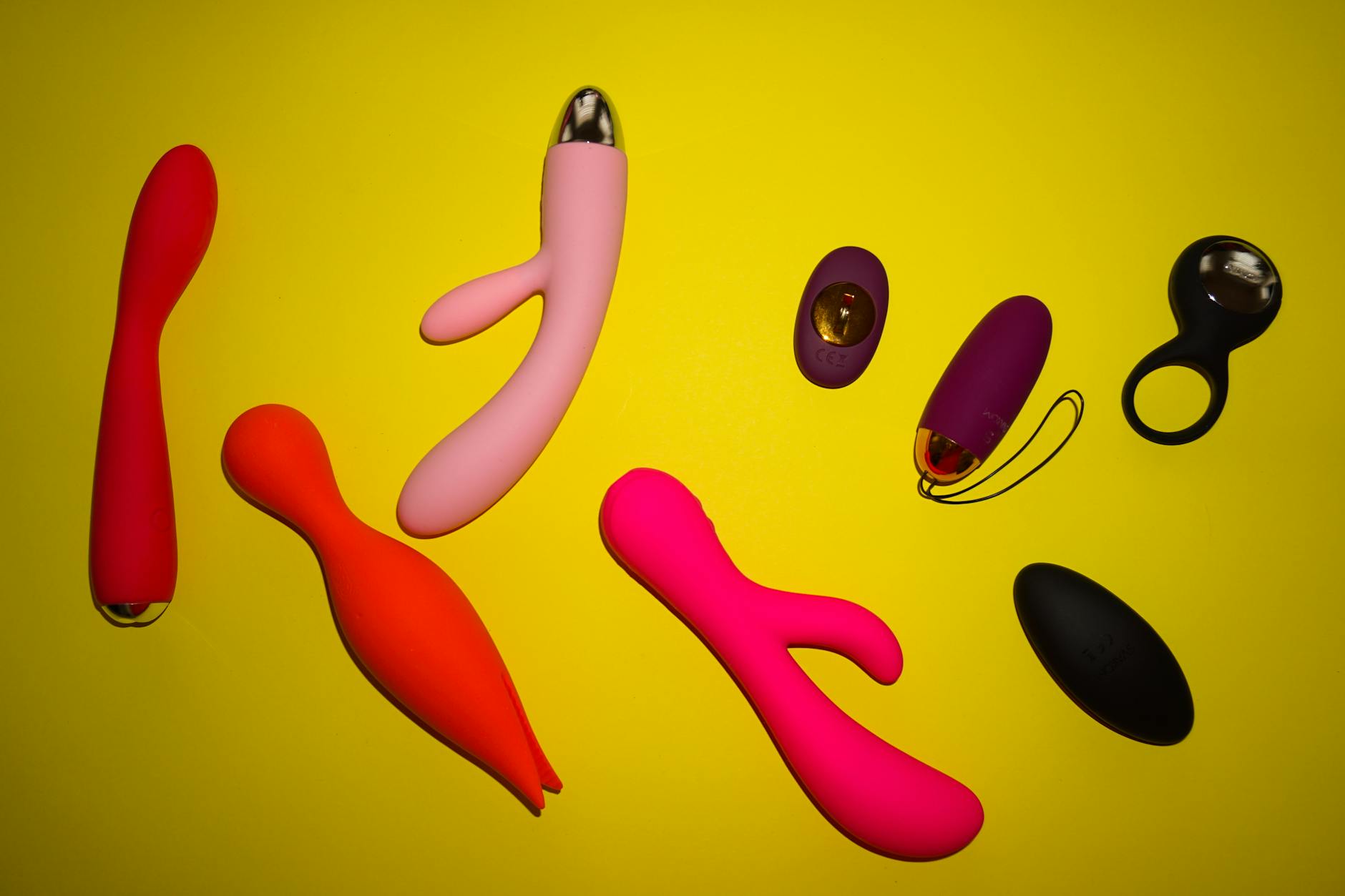 Close-up of hands holding a blue clitoral vibrator against a purple background