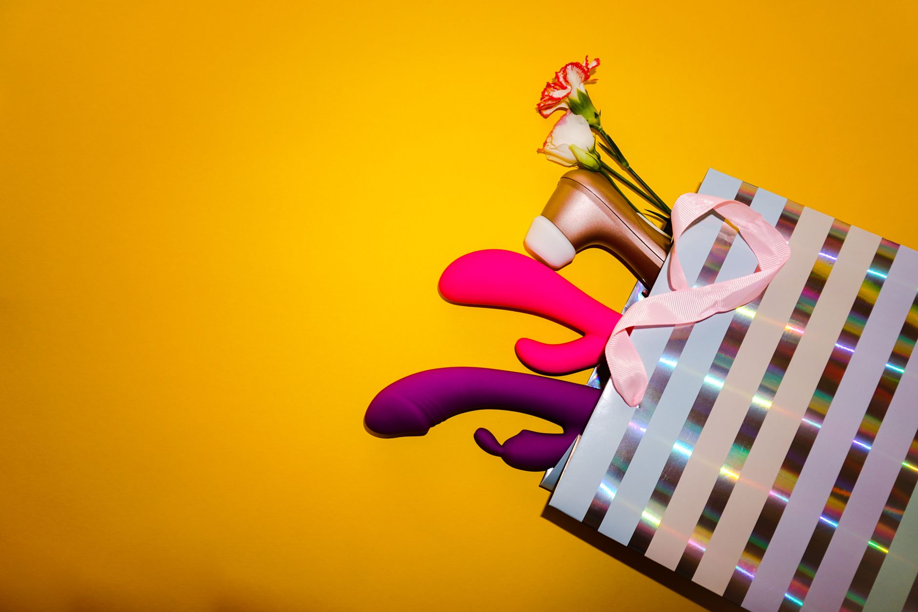 Yellow silicone vibrator surrounded by peeled bananas on a bright yellow background, representing approachability and ease